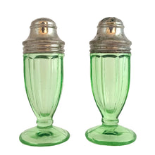 Load image into Gallery viewer, Pair of antique vintage depression era art deco uranium glass Ribbon footed salt and pepper shakers with metal lids. Crafted by Hazel-Atlas Glass, USA, 1930 - 1935. This timeless kitchen accessory and their novel green uranium glass, which glows brilliantly under black light, adds a unique accent to your kitchen and table decor!

In good vintage condition, no chips, one shaker has a horizontal scratch. Age appropriate wear to the lids.

Measures 1 1/2 x 3 3/4 inches
