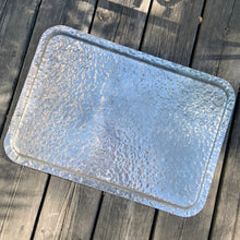 Load image into Gallery viewer, One of the pretties pieces of hammered aluminum we&#39;ve encountered! This sweet serving tray has decorative ribbon style handles detailed with floral details and embossed tulips on the tray surface (shape 423). Made by Rodney Kent, circa 1950. A great addition to your serveware or bar cart.  In excellent condition. Manufacturer&#39;s marks on the bottom.  Measures 18&quot; x 13&quot;

