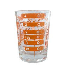 Load image into Gallery viewer, Vintage Here&#39;s Mud in Your Eye novelty bar measure featuring a clumsy fisherman and 1, 2, 3 and 4 ounce levels printed in orange on clear glass. Maker unknown, 1970s.

In as found vintage condition, no chips, some wear to inside bottom.

Measures 2 1/4 x 3 inches
