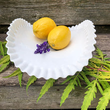 Load image into Gallery viewer, This vintage  &quot;Hobnail&quot; pressed milk glass low banana stand brings all the drama! It features a low foot, with folded sides and a crimped edge. Crafted by the Fenton Art Glass, USA, circa 1970s. A graceful piece of pressed glass in a classic pattern that will always be in style no matter your decor style. Fill with your favourite fruits and display!  In excellent condition, free form chips/cracks.  Measures 12 x 9 x 4 1/2 inches
