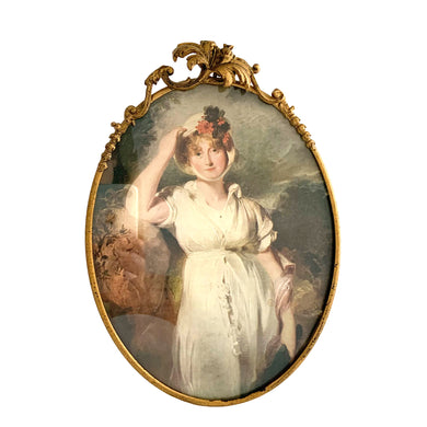Vintage mid-century Hollywood Regency ornate brass oval shaped frame featuring a three dimensional Hibiscus flower with decorative treatment holding a lithographic print of Caroline Princess of Wales by Sir Thomas Lawrence (1798). This piece has a stand so it can be displayed on a table and it also has a hanger to facilitate hanging on a wall. The back is removable making it a breeze to change the artwork. A lovely piece!  In excellent condition. Measures 7 1/8 x 10 inches