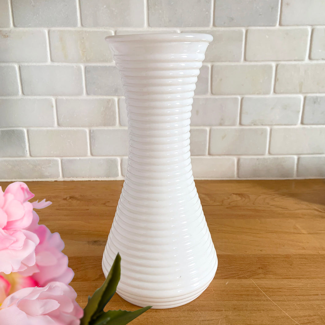 Vintage horizontal ribbed milk glass vase. Whether adorned with flowers or left bare, it adds a touch of beauty to any setting. Its timeless design makes it suitable for various decor styles, from farmhouse and shabby chic to cottage core, and perfect for wedding or bridal decorations. In excellent condition, no chips or cracks. Measure 4 x 8 3/4 inches