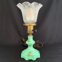 Load image into Gallery viewer, This uniquely shaped and rare vintage depression era art deco style green uranium slag glass boudoir table lamp features an octagonal base with hand painted enamel flowers in shades of pink, blue, green and brown. Created and crafted by Houze Art Glass in the USA, circa 1930. The best part is that lovely lamp glows brilliantly under black light. The lamp base with socket measures 3 7/8 x 7 inches. Original cord.
