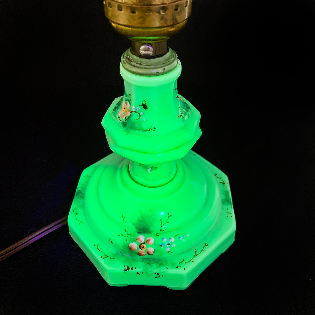 This uniquely shaped and rare vintage depression era art deco style green uranium slag glass boudoir table lamp features an octagonal base with hand painted enamel flowers in shades of pink, blue, green and brown. Created and crafted by Houze Art Glass in the USA, circa 1930. The best part is that lovely lamp glows brilliantly under black light. The lamp base with socket measures 3 7/8 x 7 inches. Original cord.