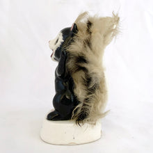 Load image into Gallery viewer, A vintage black and white ceramic skunk figurine with fluffy beige faux fur attached to its back, standing on a round white base
