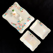 Load image into Gallery viewer, Overhead view of full Lefton pixie vanity set: large trinket box lid with reclining pixie and floral garland, flanked by two small iridescent scalloped dishes
