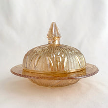 Load image into Gallery viewer, This vintage &quot;Iris Iridescent&quot; pressed marigold carnival glass covered butter dish features an intricately detailed dome with iris flowers featured on a herringbone pattern plus ribbed conical finial. It makes a lovely addition to any tablescape.  In as found vintage condition, 2 rim chips on the dish and 1 chip on the rim of the dome. Price reflect condition.  Measures 5 3/4 x 4 3/8 inches
