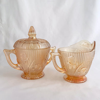 Beautifully detailed with iris flowers on a herringbone pattern this vintage pressed glass marigold coloured iridescent creamer and covered sugar makes a lovely addition to any tablescape.  In excellent condition, free from chips or cracks.  Creamer measures 3 1/2 x 3 (not including spout/handle)  Sugar measures 3 3/4 x 5 1/2 inches (not including handles)