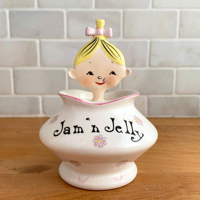 Rare vintage mid-century era Jolly Girls ceramic Jam'n Jelly jar with spoon. Holt Howard, Japan, imported by LIpper and Mann, 1950s. Add this adorable kitschy piece to your collection!

In very good vintage condition, no chips/cracks/repairs, minor discolouration on the underside of the lid where the ceramic stilt pin was placed during firing. Marked Japan.

Measures 3 3/4 x 3 3/4 x 5 1/4 inches