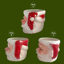 Load image into Gallery viewer, Vintage jolly red and white Santa Claus figural face ceramic mug...nostalgia from holidays gone by! Likely made for Binns Department Store in Pittsburgh, Pennsylvania and crafted in Japan, circa 1960s. Add some holiday magic to your Christmas decor by filling this charming mug with candy canes or top with an ornament!

In as found vintage condition, no chips, cracks or repairs. There is wear to the cold paint on all three mugs. Mugs A and C are marked Japan.

Measures 3 x 3 inches, not incl. handle
