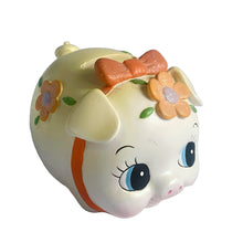 Load image into Gallery viewer, This adorable kitschy vintage Kawaii white piggy bank features a big eyed smiling face with pink bow, glittery flowers and curly tail. Crafted by Sanrio, Japan, 1980s. A wonderful collectible decor piece!

In great vintage condition, no chips or cracks. Black rubber stopper is intact.

Measures 3 1/2 x 2 3/4 x 3 inches
