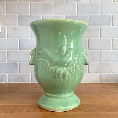 Vintage mid-century gloss light green handled vase with embossed bird, #281. Crafted by McCoy Pottery, 1946. This lovely vase is must for any art pottery collector!

In as found vintage condition, minor flea bite on interior top rim, hairline crack, no repairs, crazing commensurate with age. Maker's mark on the bottom.

Measures 6 x 8 1/4 inches