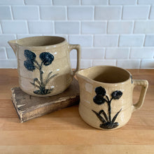 Load image into Gallery viewer, Vintage natural yellow ware strapped barrel milk pitcher featuring navy lily in bas relief with rope style handle, No. 21171. Crafted by Robinson Ransbottom Pottery Co., USA, 1930s. Enhance your home&#39;s decor with this beautiful piece of primitive farmhouse tableware. A wonderful addition to any art pottery collection!

Excellent vintage condition, no chips/cracks/repairs, age-related crazing and typical manufacturer&#39;s glaze pops. Unmarked

Option 1: 4 x 4 1/8 inches. 32 oz
Option 2: 5 1/4 x 5 1/4. 48 oz
