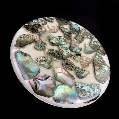 Vintage clear lucite trivet filled with iridescent abalone shells, backed in white with three bun feet. Crafted by New Trends Industries, USA. 1968.  In excellent condition. Original sticker.  Measures 5 1/2 inches