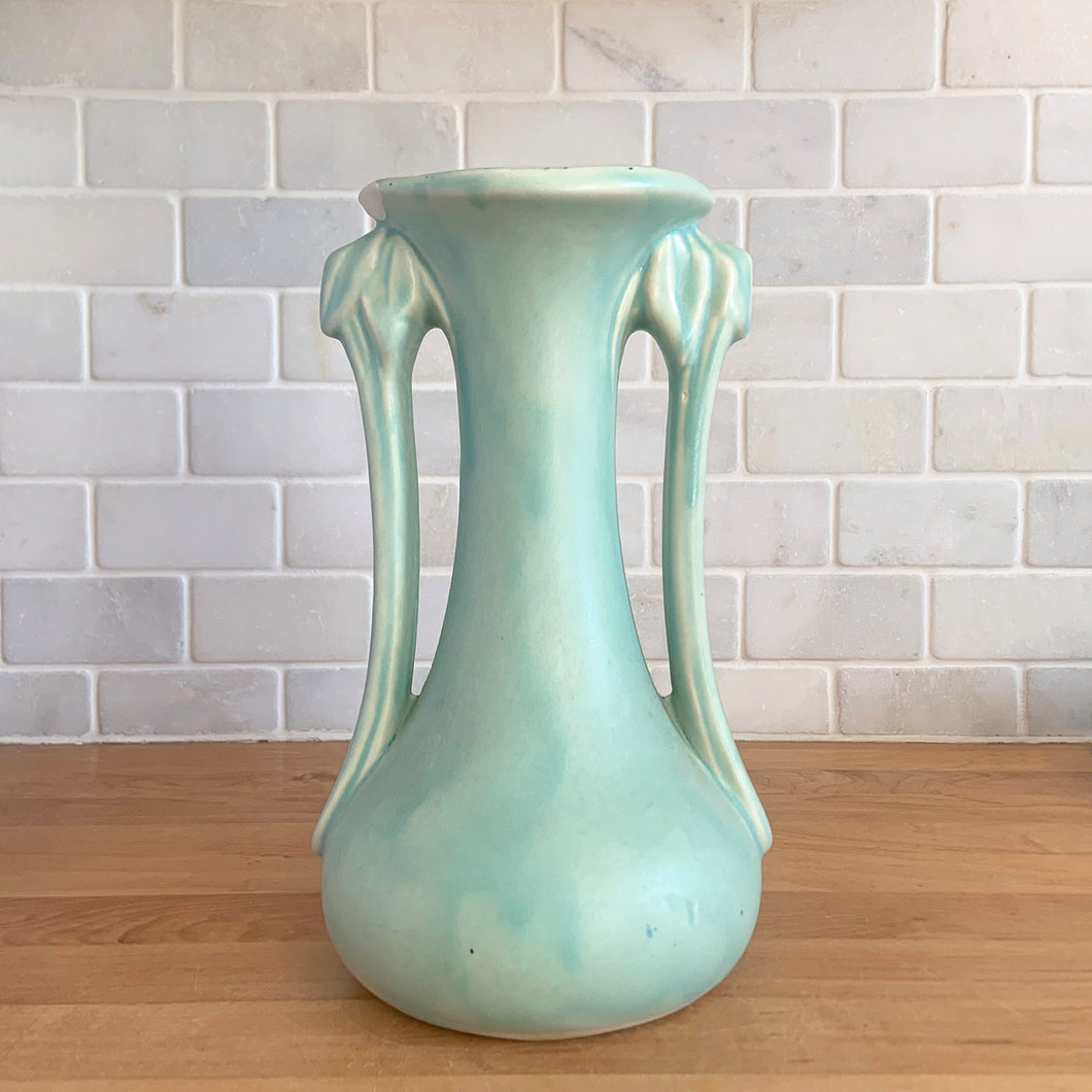 Beautiful vintage Art Deco matte aqua leaf topped handled vase. Crafted by McCoy Pottery, 1940s. This vase is must for any art pottery collector!

In as found vintage condition, area at the rim where glaze has come away, no chips/cracks/repairs. Maker's mark on the bottom.

Measures 5 1/4 x 9 1/4 inches