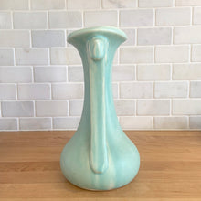 Load image into Gallery viewer, Beautiful vintage Art Deco matte aqua leaf topped handled vase. Crafted by McCoy Pottery, 1940s. This vase is must for any art pottery collector!

In as found vintage condition, area at the rim where glaze has come away, no chips/cracks/repairs. Maker&#39;s mark on the bottom.

Measures 5 1/4 x 9 1/4 inches
