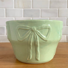 Load image into Gallery viewer, Vintage mint green embossed bows ceramic jardiniere planter, No. 287. Crafted by Robinson Ransbottom Pottery Co., 1940s. A beautiful piece to fill with your favourite houseplant and add to your art pottery collection!

In excellent vintage condition, no chips/cracks/repairs. Typical manufacturers glaze pops. Maker&#39;s mark.

Measures 6 x 4 inches
