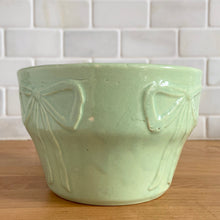 Load image into Gallery viewer, Vintage mint green embossed bows ceramic jardiniere planter, No. 287. Crafted by Robinson Ransbottom Pottery Co., 1940s. A beautiful piece to fill with your favourite houseplant and add to your art pottery collection!

In excellent vintage condition, no chips/cracks/repairs. Typical manufacturers glaze pops. Maker&#39;s mark.

Measures 6 x 4 inches
