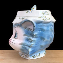 Load image into Gallery viewer, Adorable vintage hand painted Miss Priss anthropomorphic blue kitty cat head ceramic cookie jar. Lefton, Japan, 1950s. Highly sought after, this sweet cookie jar represents the epitome of collectible kitsch kitchen decor!

The vessel is in excellent condition, no chips/cracks/repairs. The lid has a repair to the top and several chips with one to the back of the flower, none detract from display or function, please see photos for details.

Measures 7 1/2 x 6 x 7 1/2 inches
