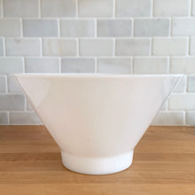 Load image into Gallery viewer, Elevate your table with this large vintage milk glass serving bowl, featuring a bold conical silhouette that embodies Modernist design. While Anchor Hocking produced a similar clear version, this piece's maker remains a mystery—adding to its vintage charm. Versatile and elegant, it's equally at home presenting a fresh salad, your favorite snacks, or as centerpiece filled with fruit. The perfect combination of nostalgia and contemporary style.

In excellent condition, no chips.

Measures 10 3/4 x 6 inches
