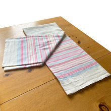 Load image into Gallery viewer, Vintage natural linen tablecloth featuring stripes in light pink, dark pink and blue. Give your table a touch of rustic charm with this grain sack style table covering. Perfect for&nbsp; farmhouse, shabby chic and cottage core decor styles.  In excellent condition, free from stains/tears  Tablecloth measures 59 x 77 inches
