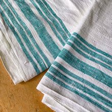 Load image into Gallery viewer, Vintage natural cotton linen tablecloth featuring wide and narrow turquoise green stripes. Give your table a touch of rustic charm with this grain sack style table covering. Perfect for farmhouse, shabby chic and cottage core decor styles.

In excellent condition, free from stains/tears

Tablecloth measures 52 x 78 inches
