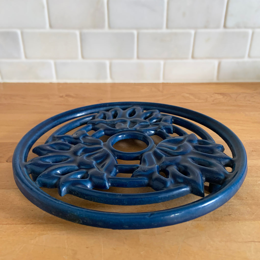Vintage navy blue round shaped cast iron trivet with lotus flowers. Made in Taiwan, 1970s. Use to safeguard your countertop and tables from hot pots and dishes, or use as wall decor. A charming and practical addition to any kitchen!

In excellent condition.

Measures 8 3/4 x 7/8 inches