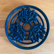 Load image into Gallery viewer, Vintage navy blue round shaped cast iron trivet with lotus flowers. Made in Taiwan, 1970s. Use to safeguard your countertop and tables from hot pots and dishes, or use as wall decor. A charming and practical addition to any kitchen!

In excellent condition.

Measures 8 3/4 x 7/8 inches
