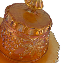 Load image into Gallery viewer, Close-up detail of Northwood Grape &amp; Cable marigold carnival glass covered butter dish, showing pressed grapevine and leaf relief on the lid and body, iridescent amber finish, c. 1910
