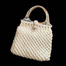 Load image into Gallery viewer, Vintage hand-knotted off-white macrame hand bag features a loop and bead closure, hard plastic handles, and satin lining. A great bohemian 70s style purse to compliment any outfit that may be carried at the elbow or shoulder. A nice sized bag for everyday or a day at the beach.

In vintage condition, needs cleaning.

The bag itself measures 14 x 13 inches and 22 inches with handles
