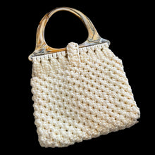 Load image into Gallery viewer, Vintage hand-knotted off-white macrame hand bag features a loop and bead closure, hard plastic handles, and satin lining. A great bohemian 70s style purse to compliment any outfit that may be carried at the elbow or shoulder. A nice sized bag for everyday or a day at the beach.

In vintage condition, needs cleaning.

The bag itself measures 14 x 13 inches and 22 inches with handles
