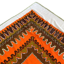 Load image into Gallery viewer, Bring retro flair to your dining room with this eye-catching linen tablecloth that screams 1970s psychedelia. Rendered in cream linen with a bold abstract pattern mixing vibrant orange, warm brown, and muted olive green, it's a statement piece that refuses to blend in. A sturdy woven trim frames the design, adding both visual interest and lasting quality. Perfect for anyone who loves vintage aesthetics and isn't afraid of a little color, this tablecloth transforms an ordinary meal into a groovy experience. 
