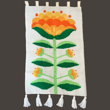 Load image into Gallery viewer, Add a pop of retro charm to your home with our Vintage Handmade Needlepoint Wall Hanging. Featuring a vibrant design of yellow, green, and orange florals on a cream background with decorative fringe, this piece is sure to catch the eye. With hanging double loop felt tabs for easy installation, bring a touch of nostalgia to any room!  In excellent condition, backed with cotton fabric.  Measures 24 1/2 x 45 1/2 (including tabs and fringe)
