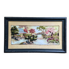 Load image into Gallery viewer, Beautifully hand stitched vintage embroidery of the &quot;Oriental Tea Garden&quot; in 100% wool yarn and framed in wood. This stunning pattern was designed by Charlene Gerrish for Sunset Designs, USA, 1982. This piece depicts the serene scene of an Asian tea house on the banks of a river featuring a bridge, cherry trees and gardens. A lovely addition to your home decor!  In excellent condition. Frame needs some touch ups.  Overall framed measurement is 22 5/8 x 13 inches  crewel
