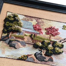 Load image into Gallery viewer, Beautifully hand stitched vintage embroidery of the &quot;Oriental Tea Garden&quot; in 100% wool yarn and framed in wood. This stunning pattern was designed by Charlene Gerrish for Sunset Designs, USA, 1982. This piece depicts the serene scene of an Asian tea house on the banks of a river featuring a bridge, cherry trees and gardens. A lovely addition to your home decor!  In excellent condition. Frame needs some touch ups.  Overall framed measurement is 22 5/8 x 13 inches  crewel
