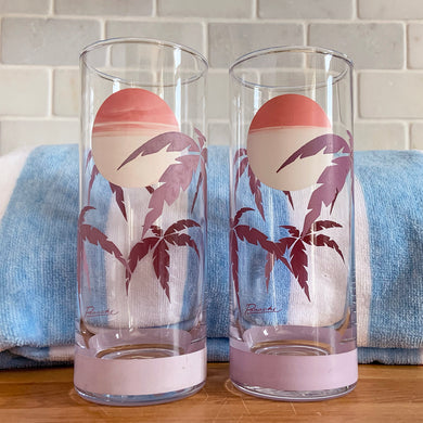The tropical graphics are the standout feature of these vintage mid-century Panache highball glass tumblers decorated with purple palm trees against a beautiful sunset. Designed by Wolly Clark, circa 1950s. These glasses will definitely add some sweet beachy vibes to your cocktails!  These glasses are free from chips/cracks with minor dishwasher damage  Measures 2 1/2 x 6 1/2 inches  Capacity 13 1/2 ounces