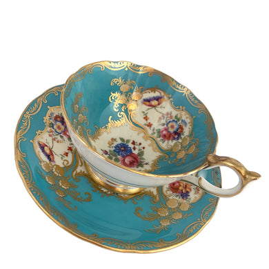 A rare vintage Bone China teacup and saucer with scalloped rim features a hand painted turquoise interior on a white ground, lavishly decorated with gold gilt filigree, complemented by colourful floral bouquets on the interior of the cup and saucer. Crafted by Aynsley, England. Backstamp indicates production between 1934 - 1950s. A stunning addition to your teacup collection!