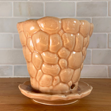 Vintage gloss peach pebble planter pot with attached saucer. Crafted by McCoy Pottery, 1950s. This rare planter is must for any McCoy art pottery collector!

In as found vintage condition, no chips, interior tight hairline crack, crazing. Marked 303 and 5 on the bottom.

Measures 5 1/2 x 5 1/4 inches