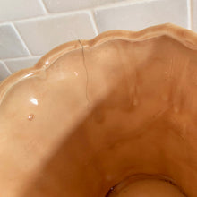 Load image into Gallery viewer, Vintage gloss peach pebble planter pot with attached saucer. Crafted by McCoy Pottery, 1950s. This rare planter is must for any McCoy art pottery collector!

In as found vintage condition, no chips, interior tight hairline crack, crazing. Marked 303 and 5 on the bottom.

Measures 5 1/2 x 5 1/4 inches
