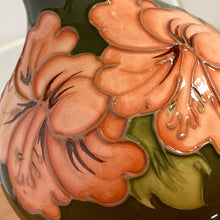 Load image into Gallery viewer, Vintage art pottery vase featuring tubelined hibiscus flowers hand painted in shades of peach on an avocado green ground. Design by Walter Moorcroft. Crafted by Moorcroft Pottery, England, 1980s. A beautiful piece for your art pottery collection or to give as a gift!  In excellent condition, no chips/cracks/repairs. Bottom has impressed marks, &quot;MOORCROFT POTTERY&quot; AND &quot;MADE IN ENGLAND&quot; and gold oval MOORCROFT, England sticker.  Measures 3 3/4 x 5 1/4 inches
