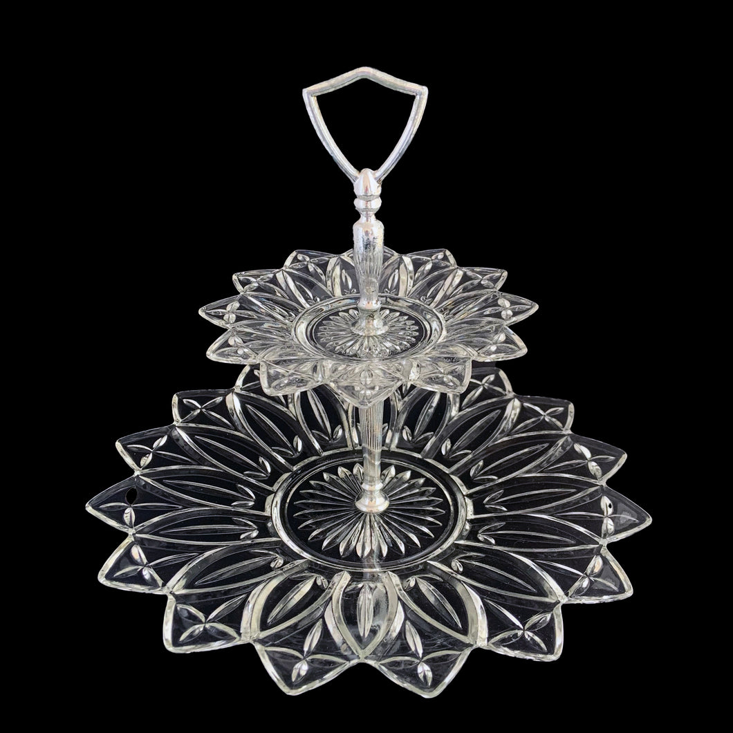 An outstanding and hard to find vintage two-tiered Petal clear glass tidbit serving tray featuring a decorative silver toned metal stem plus D-shaped handle. Crafted by Federal Glass, USA, circa 1960s. This elegant serving piece will look stunning filled with treats on any dessert table. Perfect for weddings, showers, high tea and entertaining at home.

In excellent condition, no chips, minor wear to the metal stem.

Measures approximately 11 1/2 x 9 5/8 inches