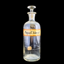 Load image into Gallery viewer, Early 20th century vintage mold blown glass pharmacy chemist apothecary jar with stopper. The hand written label reads Aqua Chlorof in black ink and has a red border which is varnished. These bottles were manufactured to house chemical compounds in pharmacies...a cool piece of history!

In as found condition with age appropriate wear.

Measures 2 3/4 x 8 3/4 inches
