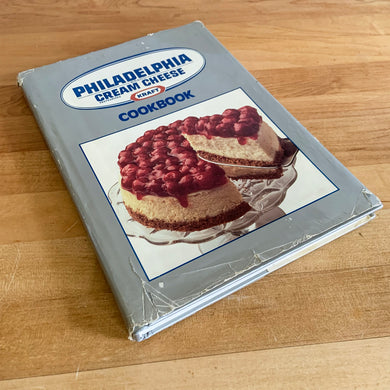 This vintage hardcover cookbook features recipes using Philadelphia Brand Cream Cheese, one of the most recognizable brands around the world. Its 200 pages are filled with amazing  recipes along with many colour photographs. Published for Kraft Inc., by Publications International USA, 1988.   In vintage condition with normal age-related yellowing, binding has cracked.   