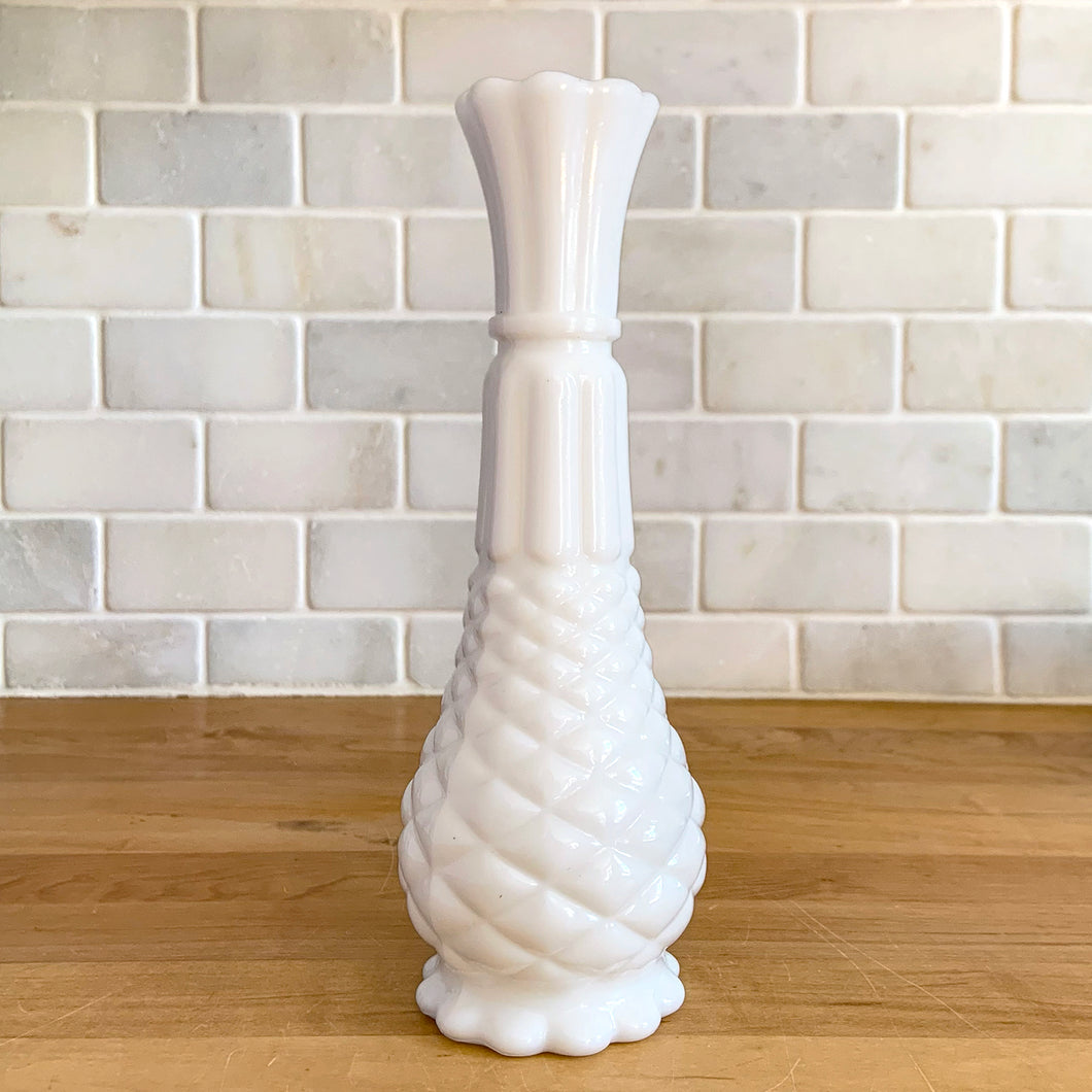 A very popular piece, this vintage milk glass bud vase has distinct pineapple shape with diamond and fluted details finished with a scalloped edge. Crafted by Anchor Hocking, USA, 1960s. Create a show stopping flower arrangement in this elegant white vase. A perfect addition to your cottage, farmhouse or wedding decor.

In excellent condition, no chips.

Measures 9 inches