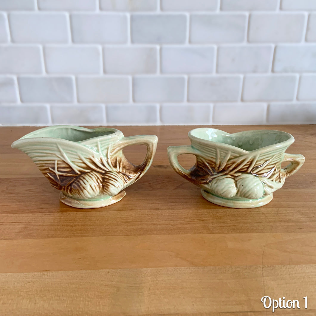 Striking vintage gloss glazed Pinecone sugar and creamer in shades of green and brown. Crafted by McCoy Pottery, 1946. Complete your tea set with this rare set, a must for any McCoy art pottery collector. Makes a nice complement to your Christmas, cottage or lodge decor!

Option 1: Creamer measures 5 5/8 x 3 1/4 x 2 7/8 inches. Sugar measures 5 1/2 x 3 3/8 x 2 3/4 inches. In excellent condition, no chips/cracks/repairs, age-related crazing. Maker's mark.