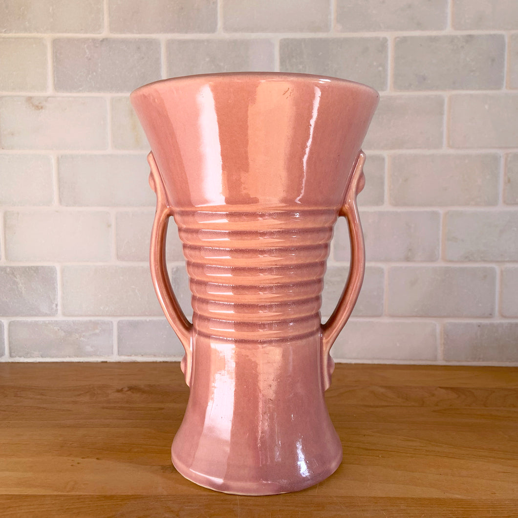 Vintage gloss pink art deco trumpet vase with ribbed design and strap handles. Crafted by Brush McCoy Pottery, 1940s. This rare vase must for any art pottery collector!

In excellent vintage condition, no chips/cracks/repairs. Marked on the bottom, Brush  USA 579 8.

Measures 5 5/8 x 8 1/4 inches