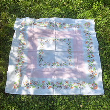 Load image into Gallery viewer, This unique cotton tablecloth has a wide central pale pink band, bordered in beautiful florals in shades of pink, burnt orange, green and gray. This dreamy linen will look amazing on any table, or use as a ground cloth for a pretty picnic scene. Use your imagination to repurpose into pillows or wearables.  In excellent condition, free from tears or stains. Circa 1950s. Measures 44 x 46 inches
