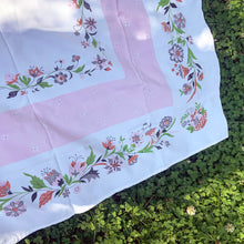 Load image into Gallery viewer, This unique cotton tablecloth has a wide central pale pink band, bordered in beautiful florals in shades of pink, burnt orange, green and gray. This dreamy linen will look amazing on any table, or use as a ground cloth for a pretty picnic scene. Use your imagination to repurpose into pillows or wearables.  In excellent condition, free from tears or stains. Circa 1950s. Measures 44 x 46 inches
