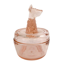 Load image into Gallery viewer, Vintage Jeannette Glass pink depression glass powder jar with lid, left side profile view, showing the Scottie dog finial in profile with pointed ears and upturned snout, textured fur moulding, flat lid with concentric ring detail, rounded barrel base
