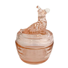 Load image into Gallery viewer, Vintage Jeannette Glass pink depression glass powder jar with lid, rear view, showing the seated terrier dog finial facing right with pointed ears, open mouth, and curly textured fur body, flat domed lid, ribbed rounded base in blush pink glass
